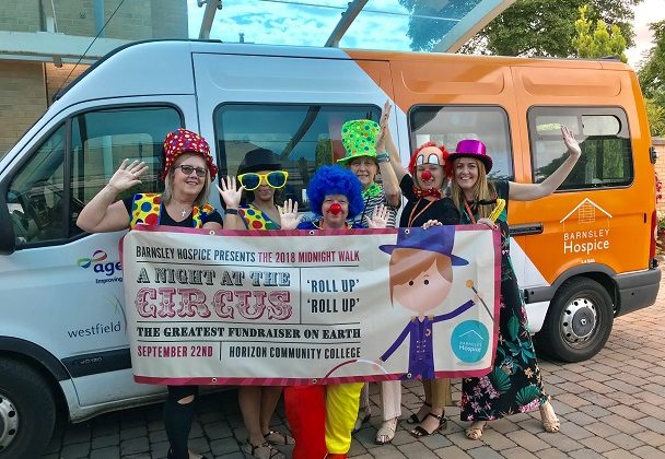 Photo of the Barnsley Hospice team dressed in circus clothing holding a banner which says A night at the circus.