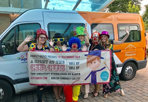 Photo of the Barnsley Hospice team dressed in circus clothing holding a banner which says A night at the circus.