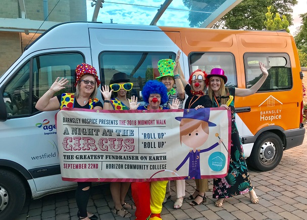 Photo of the Barnsley Hospice team dressed in circus clothing holding a banner which says A night at the circus.