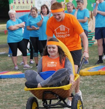 man pushing woman in wheelbarrow as part of It's a Knockout event