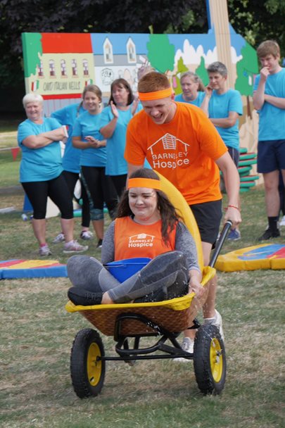 man pushing woman in wheelbarrow as part of It's a Knockout event