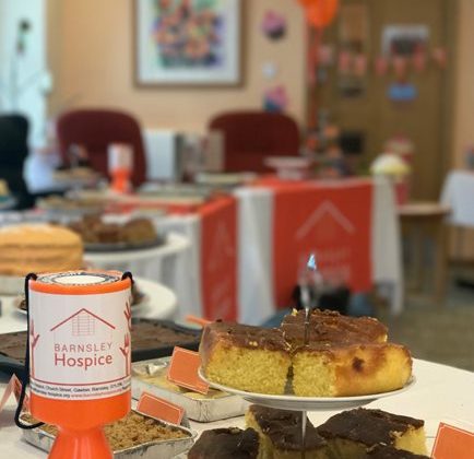 Photo of cakes on a a cake stand with a Barnsley Hospice donation box.