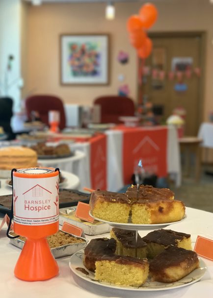 Photo of cakes on a a cake stand with a Barnsley Hospice donation box.