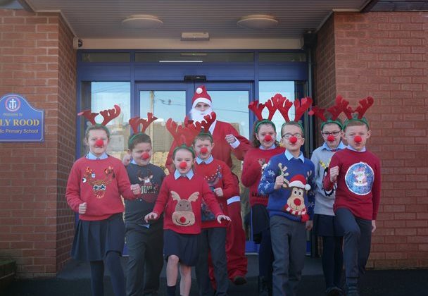 Photo of children from Holy Rood Primary School with their teacher. The children are dressed in Christmas jumpers and antlers.