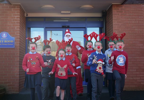 Photo of children from Holy Rood Primary School with their teacher. The children are dressed in Christmas jumpers and antlers.