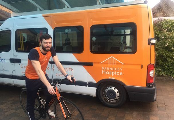 Photo of Craig Fletcher on a bicycle next to the Barnsley Hospice mini bus