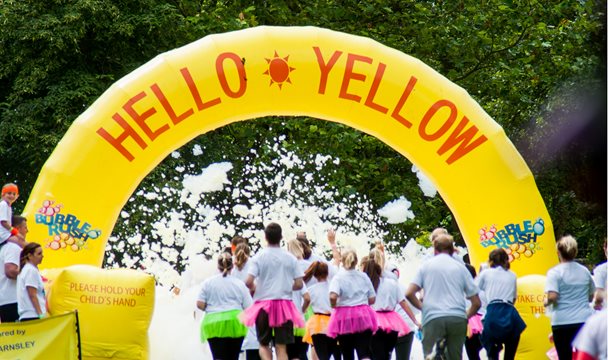 Photo of a group of fun runners setting off. Some of them are wearing bright pink and bright green tutus.