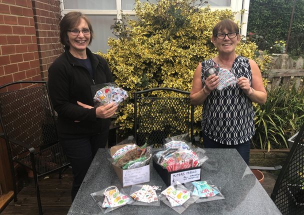 Photo of Janet Mellor and Jocelyn Feetham with their colourful handmade face masks displayed on a table.