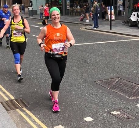 Photo of a lady running in a race and wearing a Barnsley Hospice vest.
