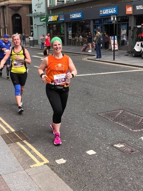 Photo of a lady running in a race and wearing a Barnsley Hospice vest.