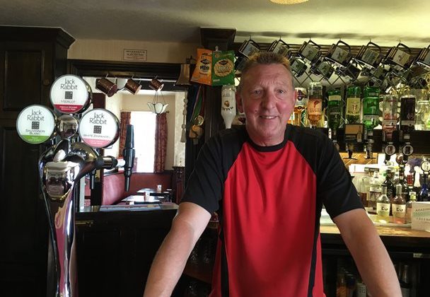 Photo of Phil Hickling behind the bar in his pub.