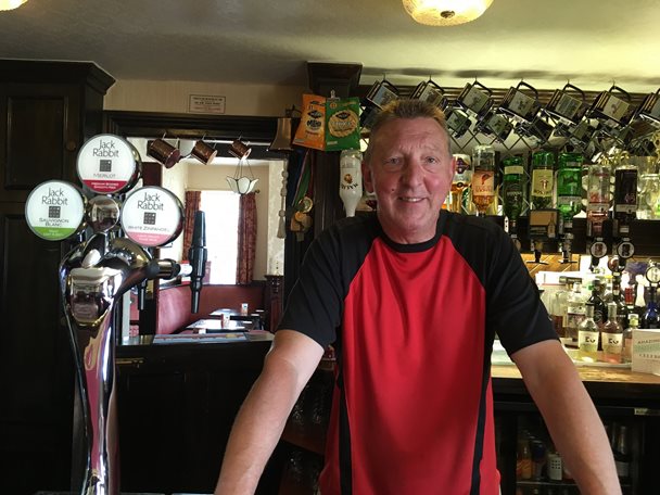 Photo of Phil Hickling behind the bar in his pub.