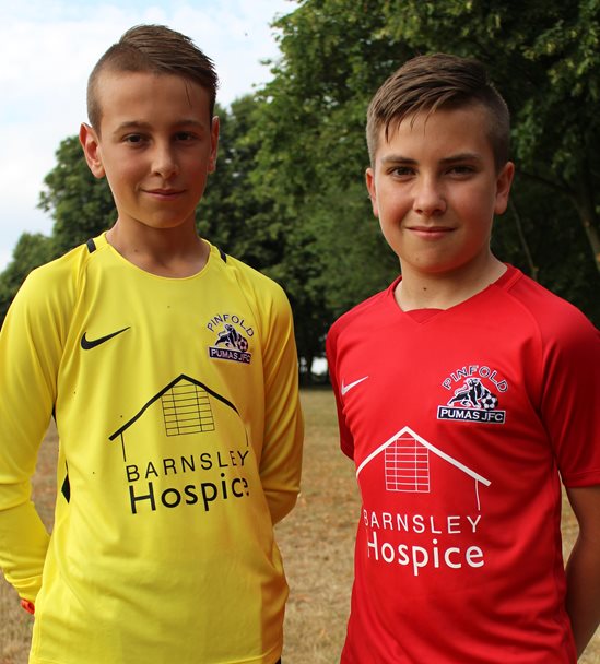 Photo of two boys wearing. One of them is wearing a red football shirt and the other a yellow shirt. The shirts have the Barnsley Hospice logo on them.