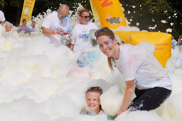 Photo of a lady and little girl having fun in the foam at the bubble rush event.