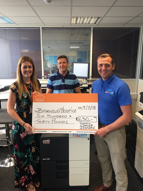 Photo of a member of the Barnsley Hospice team accepting a donation from two gentlemen from local business Copier Systems.
