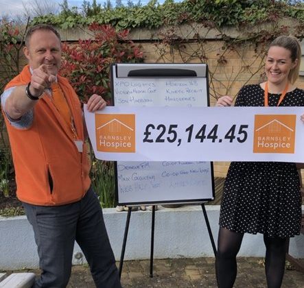 Photo of Simon Atkinson and Sam Silverwood from Barnsley Hospice. They are holding a banner which reads a donation amount of £25,144.45