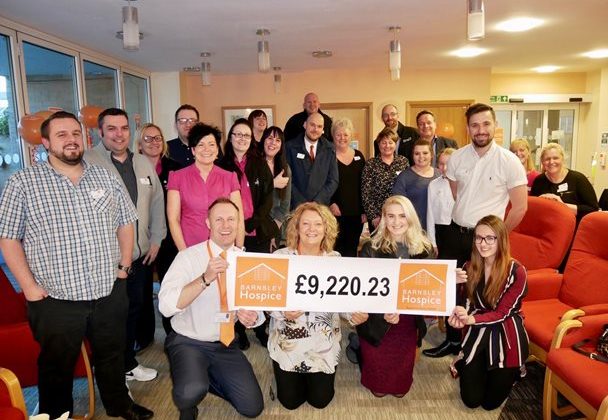 Photo of a group of people from local businesses with Barnsley Hospice. The Hospice team are holding a banner with a donation amount of £9,200.23.