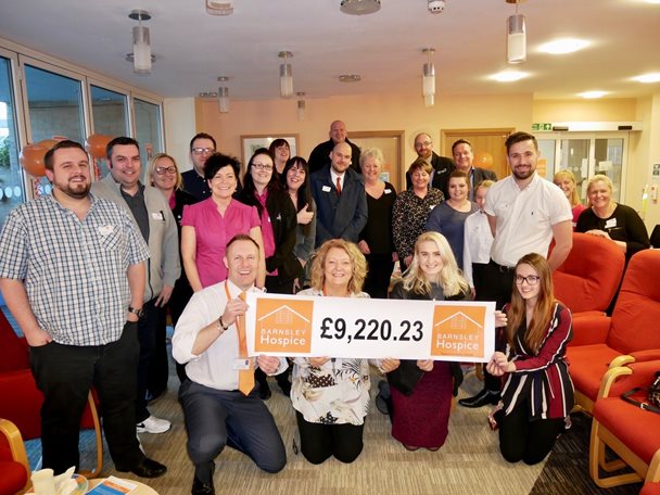 Photo of a group of people from local businesses with Barnsley Hospice. The Hospice team are holding a banner with a donation amount of £9,200.23.