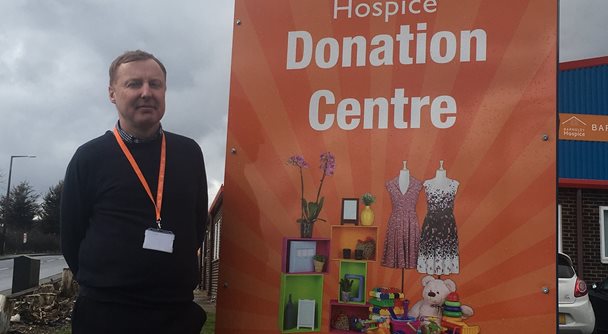 Photo of Stephen Hatfield standing next to a Barnsley Hospice Donation Centre banner