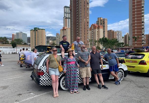 Photo off a group of people standing in front of a rally car.
