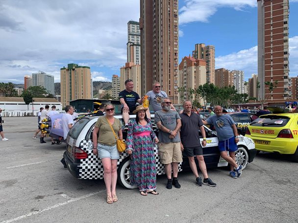 Photo off a group of people standing in front of a rally car.