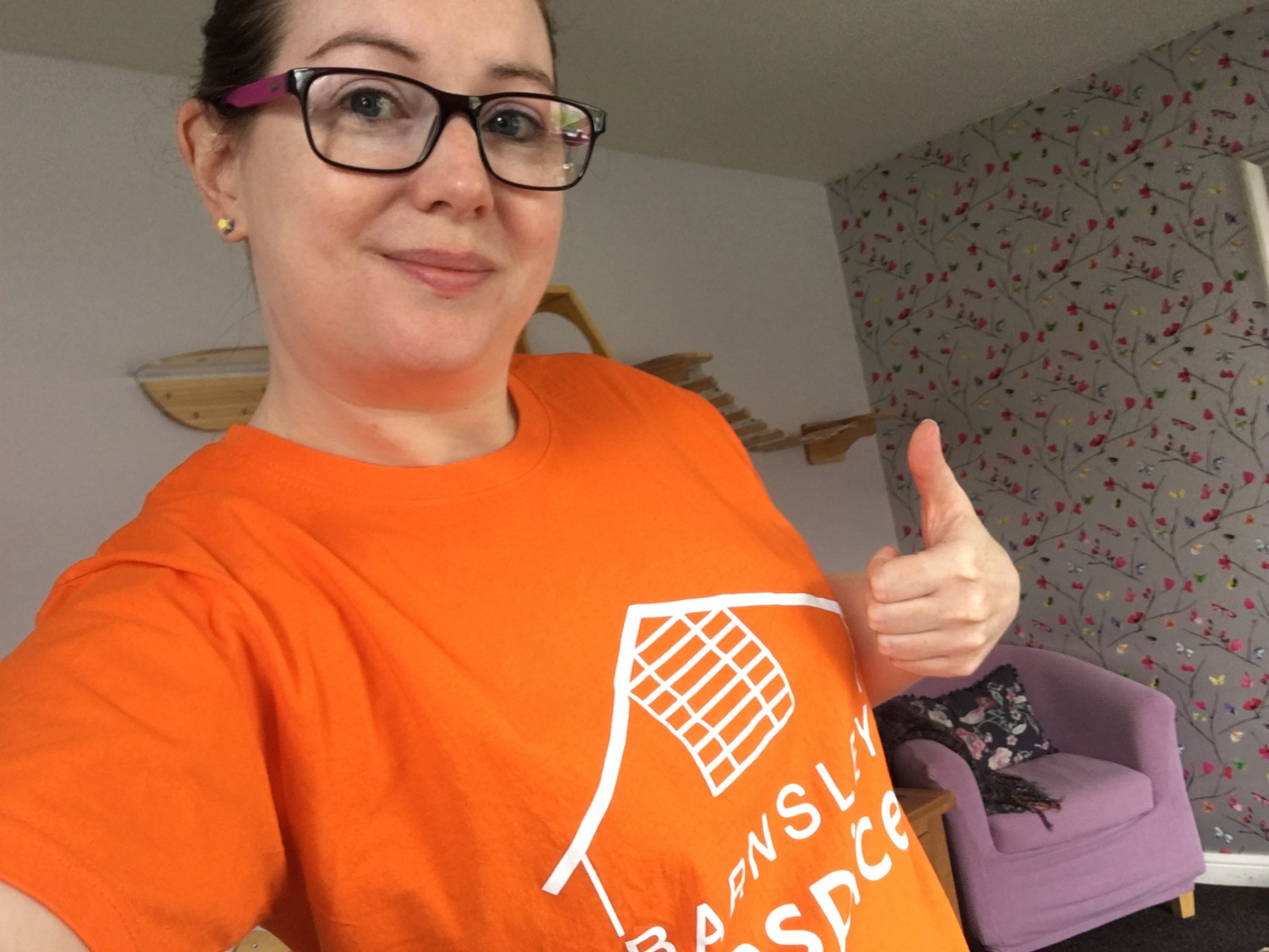 Photo of a lady wearing an orange coloured Barnsley Hospice t-shirt and doing a thumbs up sign