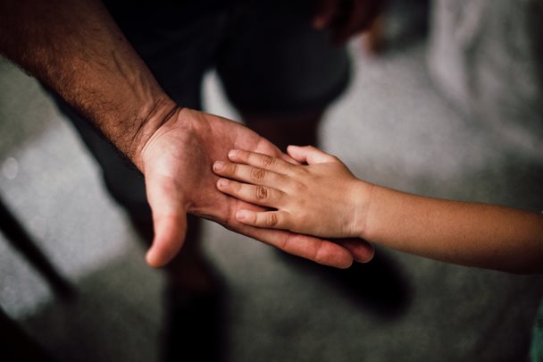 Photo of an adult's hand being touched by a child's hand