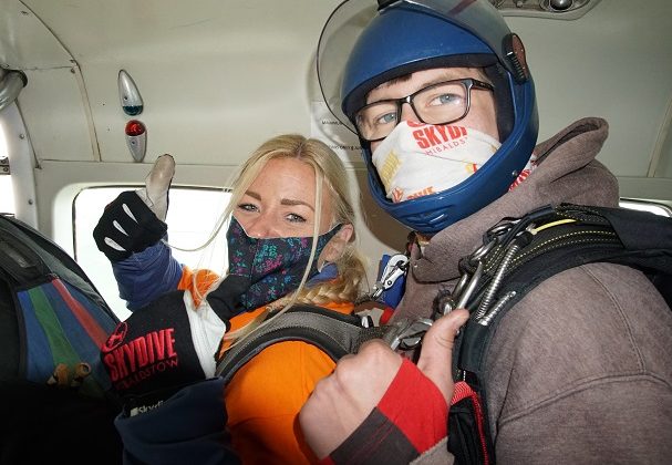 Photo of Naomi in an aeroplane doing a thumbs up sign just before doing her tandem skydive