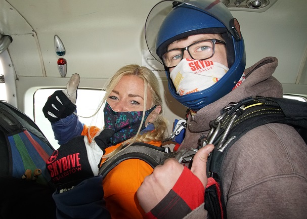 Photo of Naomi in an aeroplane doing a thumbs up sign just before doing her tandem skydive