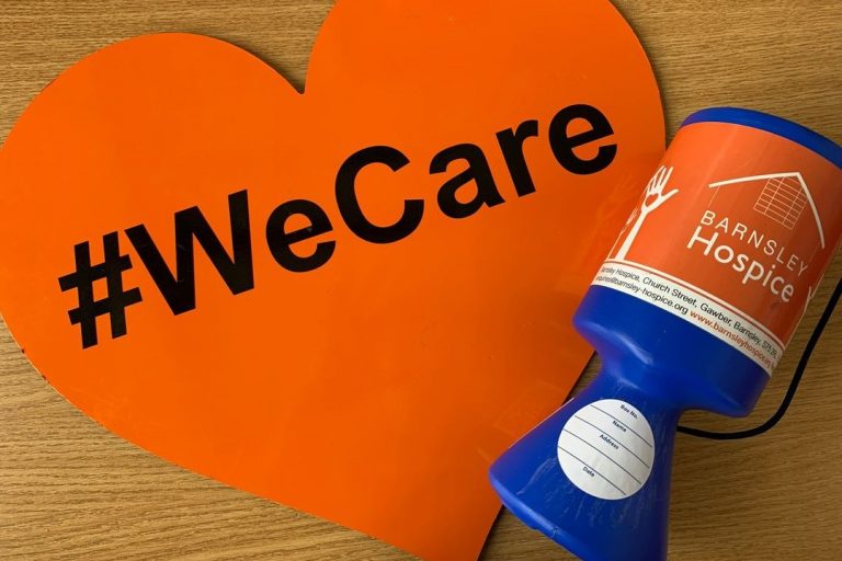Photo of a heart shaped We Care sign and a Barnsley Hospice collection box