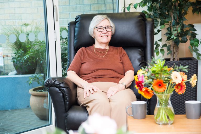 Photo of a lady sat in a chair in the Hospice orangery