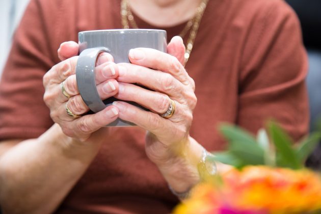 A close up photo of a hands holding a cup of tea