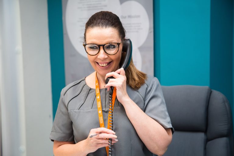 Photo of a lady answering the telephone on the Barnsley Hospice reception desk