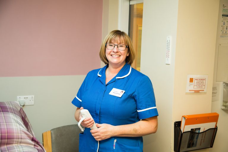 Photo of a member the Barnsley Hospice nursing team, smiling and standing in one of the patient rooms
