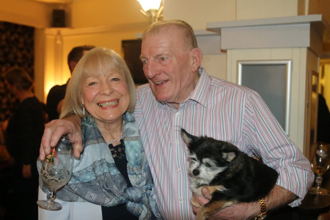 man and woman smiling with dog