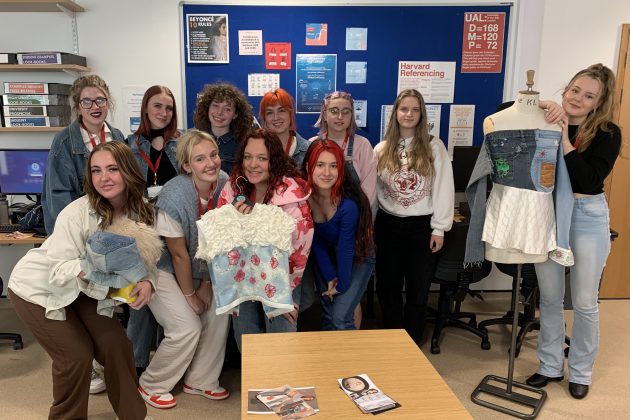 Photo of a group of Barnsley College students in a classroom holding the garments they have made from preloved denim clothing donations