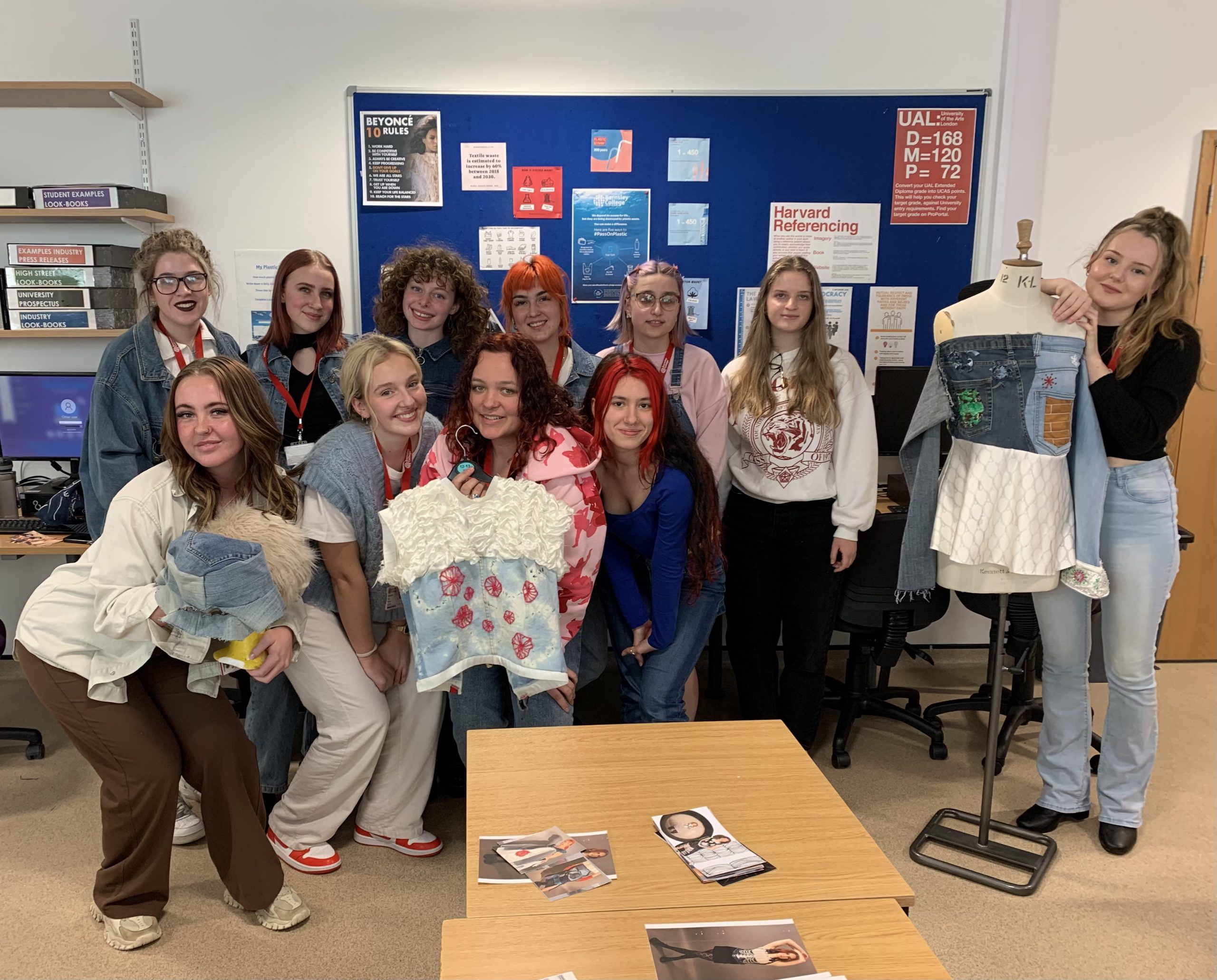 Photo of a group of Barnsley College students in a classroom holding the garments they have made from preloved denim clothing donations