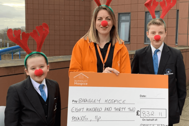 Schoolchildren present their donation dressed in antlers and a red nose to a member of the Barnsley Hospice team