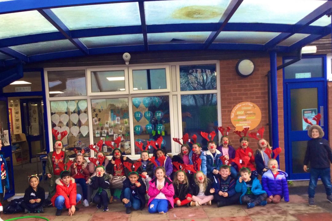 A group photo of the children who took part in the Rudolph run fundraising event. The children are wearing antlers and a red nose.