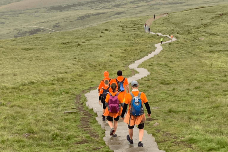 Group of fundraisers walking down a mountain in orange hospice t-shirts