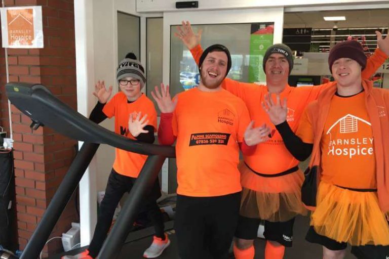 A photo of three men and a boy wearing hospice t-shirts and taking part in the Treadathon event