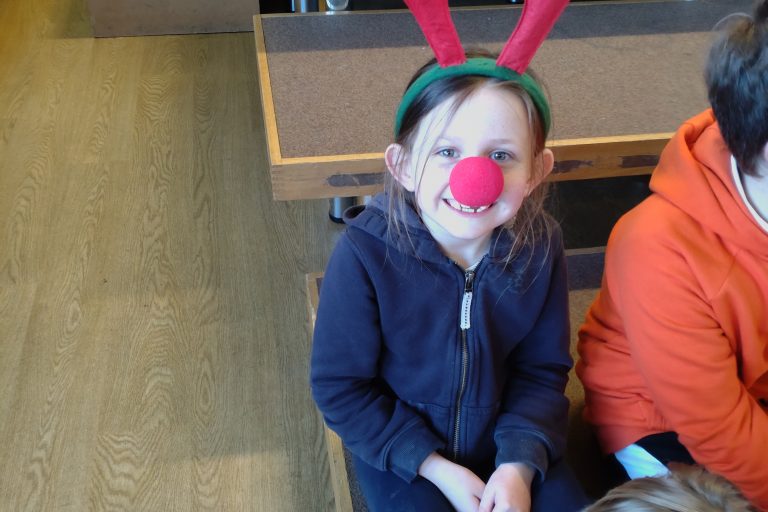 A photo of one of the children from St Mary's school wearing antlers and a red nose as part of the Rudolph fun run event