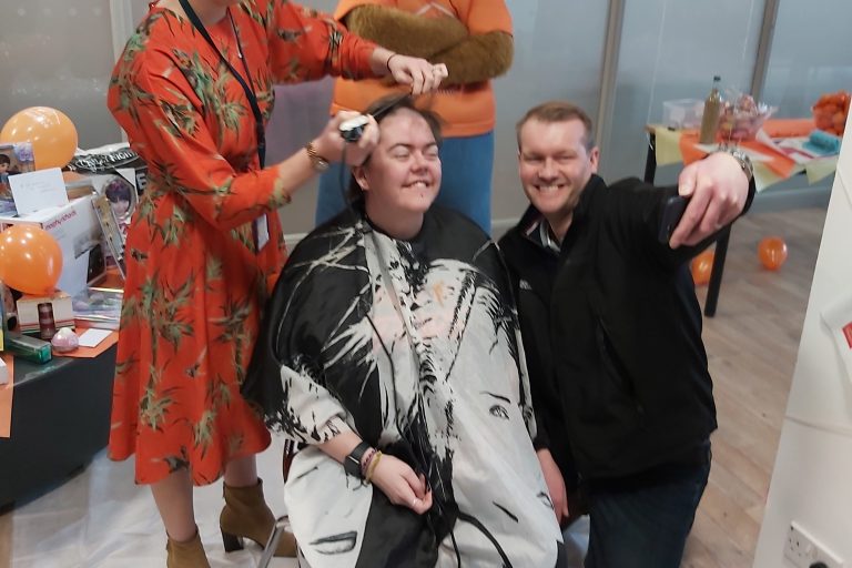 Photo of a person having head shaved as part of a fund raising event
