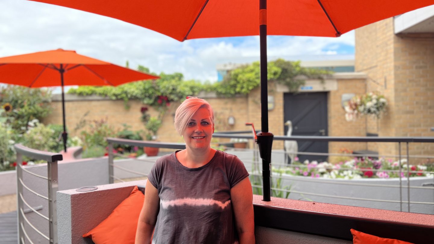 Caroline sat in the hospice garden underneath orange parasol