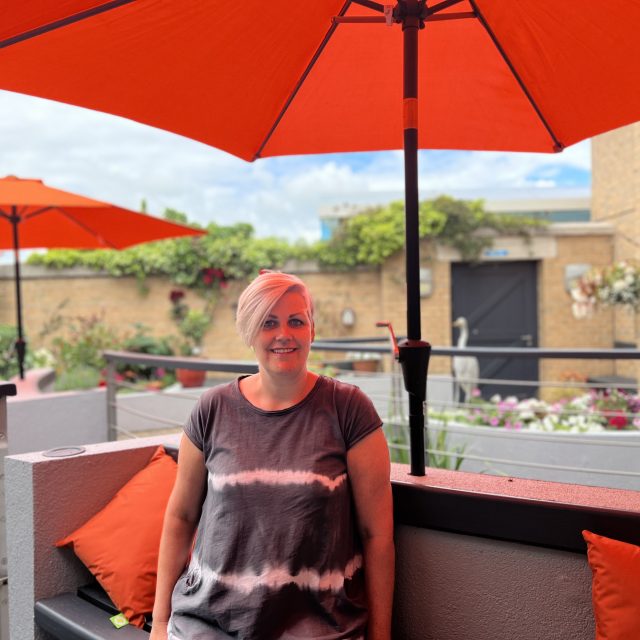 Caroline sat in the hospice garden underneath orange parasol