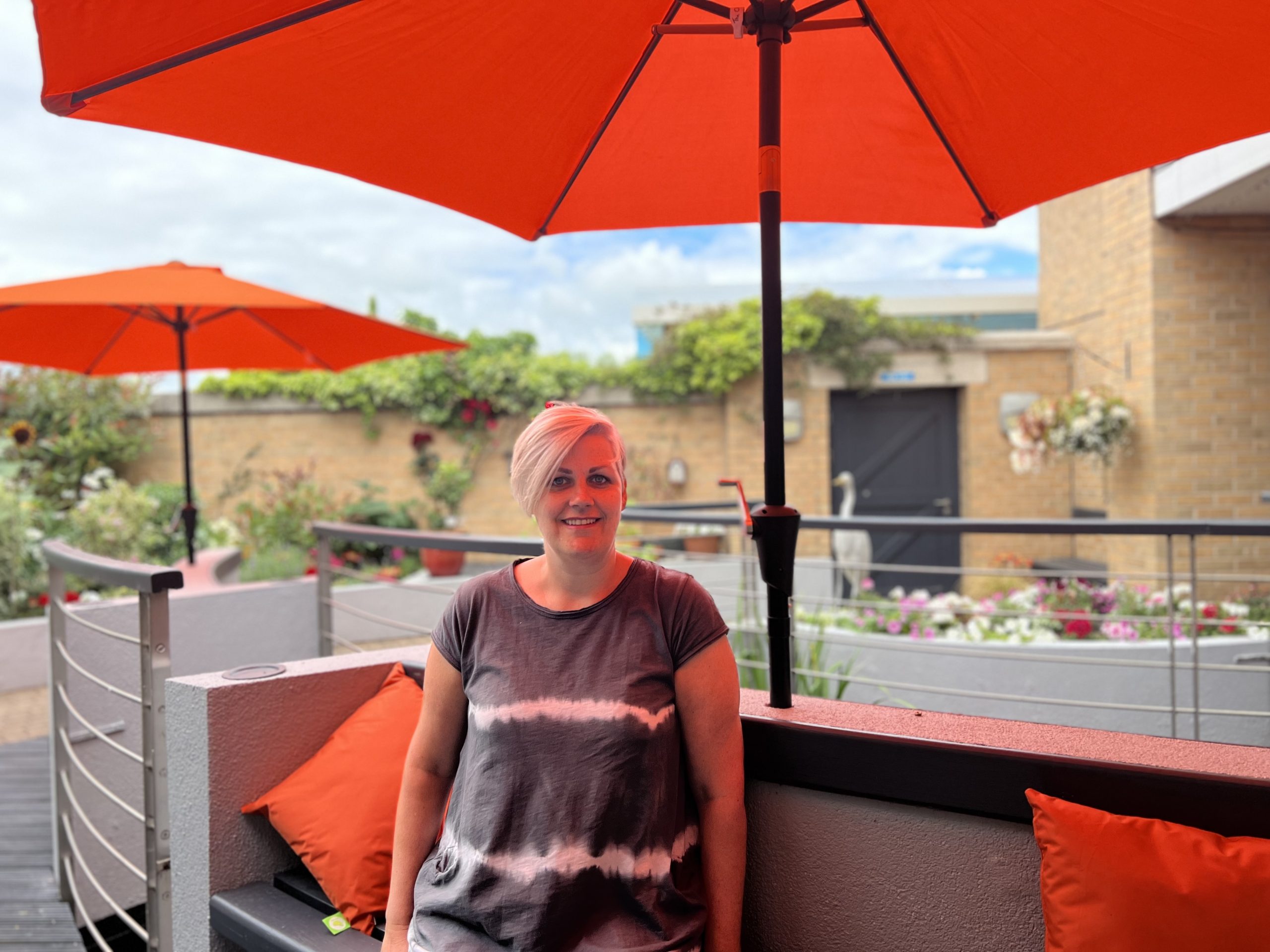 Caroline sat in the hospice garden underneath orange parasol