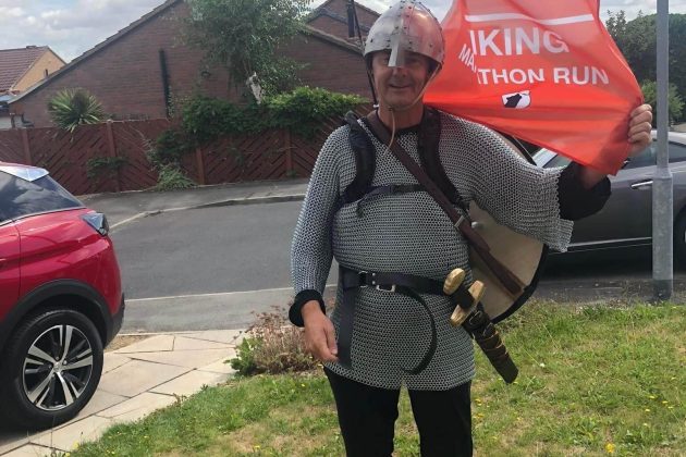 Paul dressed as a Viking holding an orange hospice flag