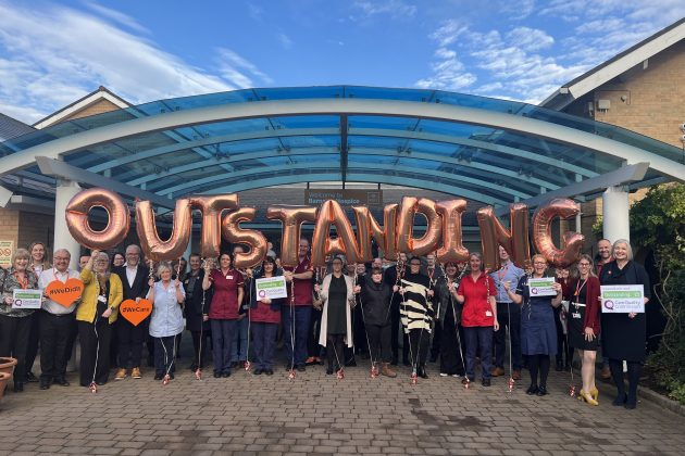 Hospice staff outside hospice with balloons spelling 'outstanding' in foreground