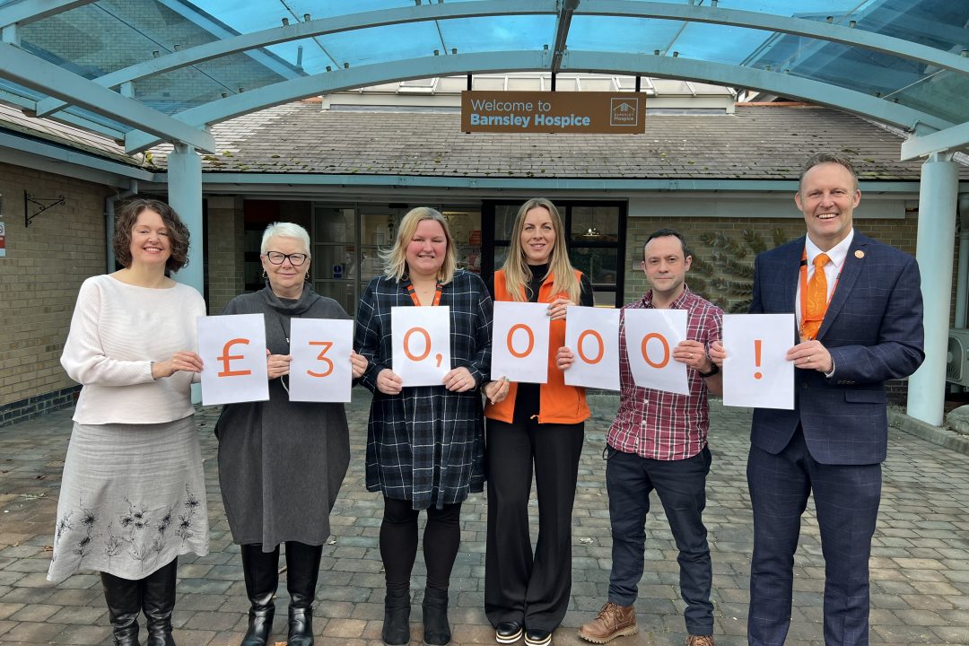 group of smiling people holding signs reading £30,000!