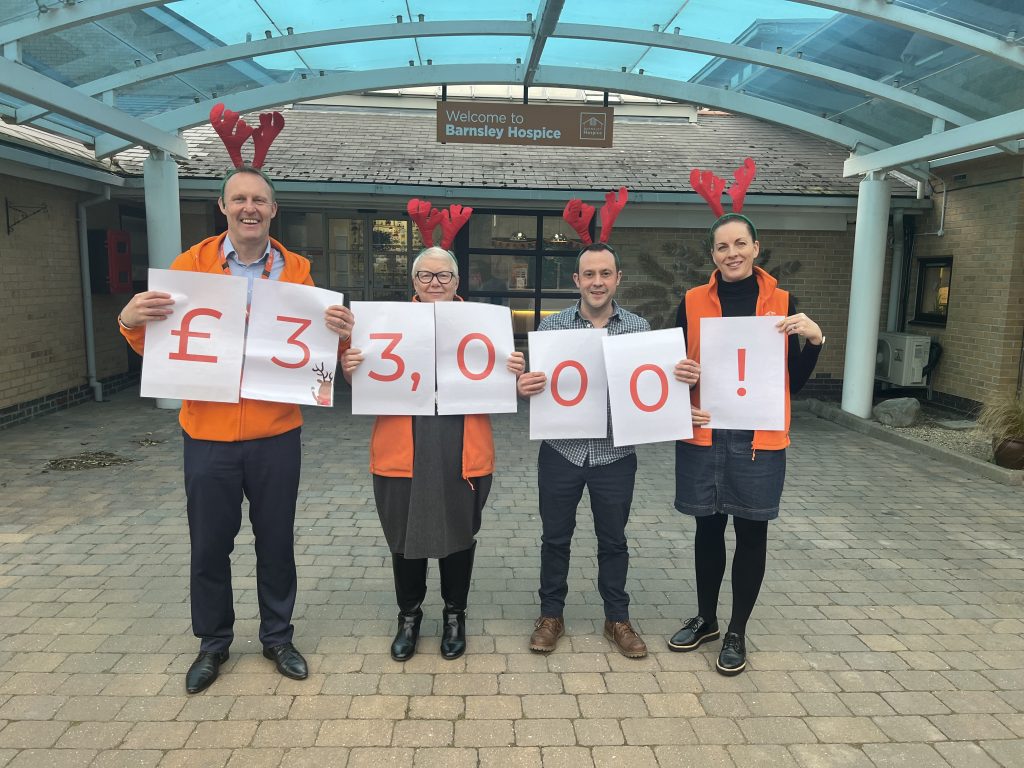 Hospice fundraiser wearing antlers and holding a sign that says "£33,000"